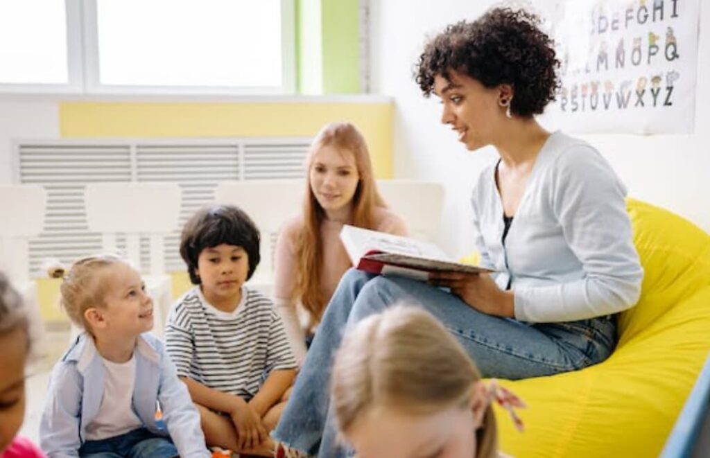 A teacher reading a book to a group of children in a colorful classroom