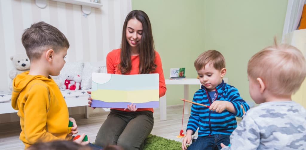 women holds a picture for three children in a room with toys