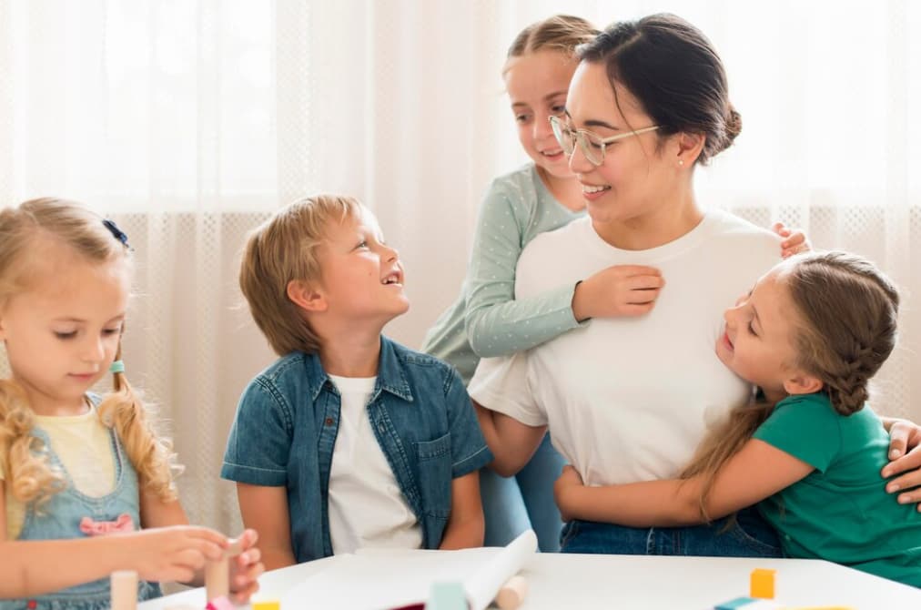 woman in glasses among the smiling children in the kindergarten