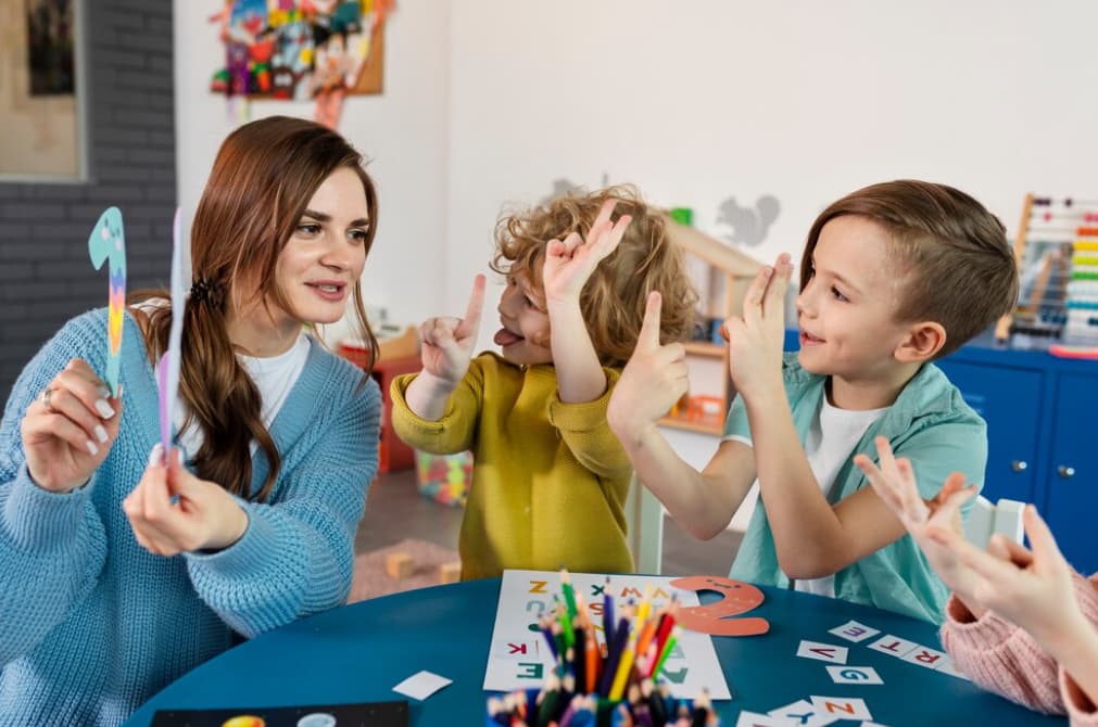 A woman plays a counting game with laughing children in a playful room setting